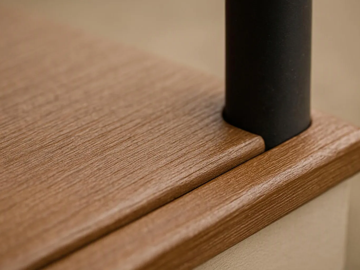 Close-up of a wood shelf meeting a black metal post against a beige wall